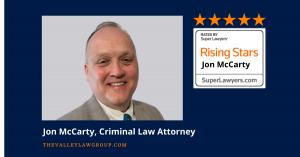 Attorney Jon McCarty poses beside his Super Lawyers Rising Star award badge for criminal defense law in Arizona.