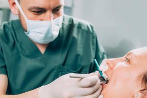 A close-up of a dentist examining a patient’s teeth to assess cavities and prepare for a filling procedure.