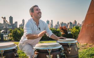 The photo shows a happy musician playing the congas.