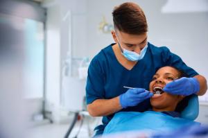 A Black woman receives professional dental care from a male dentist