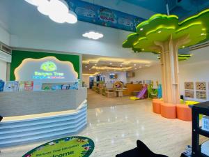 Interior of Banyan Tree Education kindergarten with a tree-themed reception area, colorful seating, play equipment, and educational wall displays in a bright, open space.