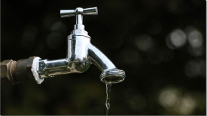 Close-up of a metal water faucet dripping water, symbolizing water loss and the importance of efficient water management systems.