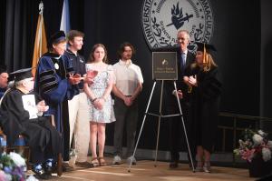 Surrounded by her husband, Chris, Immaculata University President Barbara Lettiere, along with students and faculty, Theresa unveiled the plaque for the new Major-Payton School of Business during commencement.
