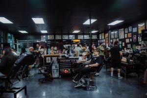 Interior of Golden Child Tattoo & Piercing Shop showing tattoo artists, piercers and clients engaged in live sessions at the Escondido, California studio.