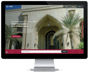 Computer screen displaying the redesigned AUIB website homepage, featuring a grand arched entrance, palm trees, and a prominent call-to-action button with streamlined navigation.