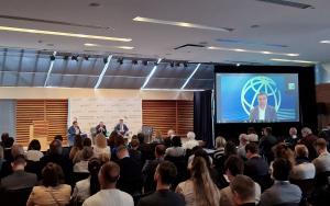 Four panelists from the "Business in Ukraine" panel discussion at the 2025 NATO Association of Canada "Safeguarding Ukraine's Future" Conference in Toronto with one panelist on a large video screen and a large audience of over 150 listeners seated