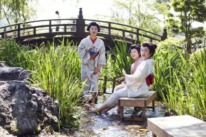 Visitors dressed in Edo-period clothing cooling off by a stream at Edo Wonderland during a traditional summer festival.