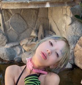 Ivory Estella Balliol, multi-media artist headshot. A beautiful young female, 24, with fair skin and blonde and blue hair, with piercings in her nose and full lips, with glitter under her eyes 