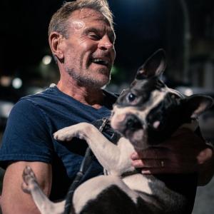 Chef Karl Wilder smiling widely while holding Milou, his Boston Terrier