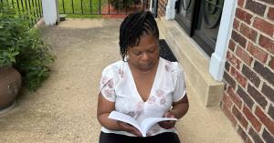 Jonnice Cooke sitting on her porch, deeply engaged in reading her memoir Unpacking the Weight Within