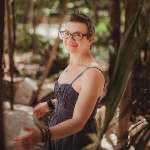 Candid outdoor portrait of Kelly Seitz, spiritual guide, somatic healer, and featured author in the international #1 bestselling anthology Whispers of the Soul: Stories of Resilience, Awakening, and the Power of Healing from Within. She stands in a forest