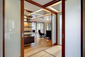 Indoor space in a flexible Brisbane home with sliding frosted glass doors, open shelving, and timber floors, designed for multi-use living.