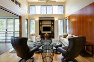 Living room with high ceilings, clerestory louvre windows, and sliding doors connecting to adjacent rooms in a post-war home renovation by dion seminara architecture.