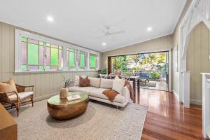 Living room in an East Brisbane character home featuring polished timber floors, open-plan design, stained glass windows, and seamless connection to an outdoor deck.