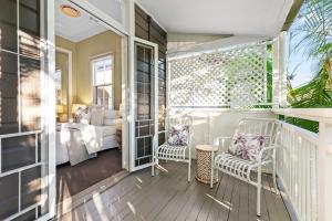 Private verandah off bedroom with white lattice privacy screen and two white metal chairs with cushions, offering a quiet retreat.