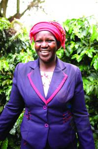 Jane, a woman coffee farmer in Kenya, smiling in a coffee field.