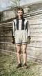 Colorized photo of Pat White standing in racing attire—striped jersey, shorts, gloves, and leather shoes—on a grassy field with wooden bleachers in the background.