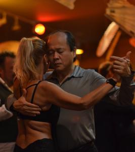Chan Park dancing tango in deep concentration during a milonga, captured in an intimate moment of connection and presence.