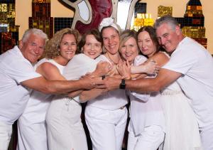 A tight-knit group of Prosperity Of Life distributors posed with heads touching and arms around each other, capturing unity and shared purpose.