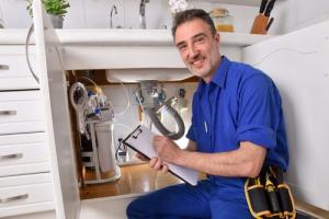 Plumber inspecting and recording sink connections