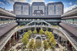 In a striking display of how innovation is redrawing the boundaries of real estate investing, LPShares Exterior view of The Crescent office complex in Dallas, featuring a symmetrical layout with French-inspired architecture, a tree-lined courtyard, café seating, and arched retail walkways—highlighting the property involved in LPShares' $1M LP exit.