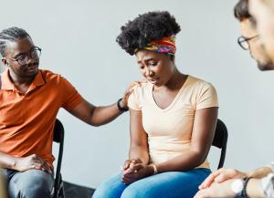 Image of an African woman being comforted by and African man.