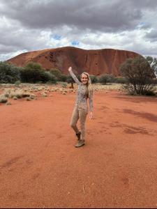Kerrie Young standing near Uluru (Ayers Rock) in Australia, symbolizing her location-independent lifestyle and success with an online business.