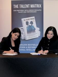 Dr. Soha Chahine and Dr. Ghenwa Habbal seated, signing their book The Talent Matrix Playbook together during the launch event.