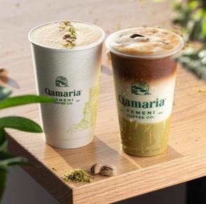 Two signature Yemeni drinks from Qamaria Coffee on a wooden table, showcasing rich textures and ingredients like pistachio.
