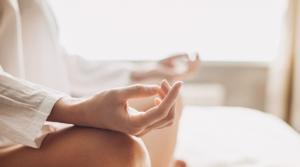 Close-up view of woman's crossed legs and folded hands in meditation pose