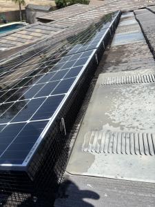 Close-up of bird-proofing mesh installed around rooftop solar panels in Visalia, CA to prevent pigeons from nesting underneath