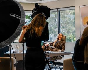 The Hollywood Reporter recently featured an exclusive profile of Adriana Gallardo, the powerhouse entrepreneur and founder of Adriana’s Insurance Adriana Gallardo sitting confidently at her desk during a photoshoot, surrounded by lighting equipment and crew members in an office setting.