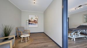 Interior of Cosmetique’s Joondalup clinic with two waiting chairs, a treatment table and modern decor.