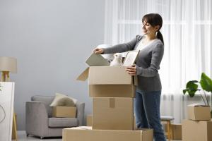 A young woman unpacking boxes in a sparsely furnished flat, symbolising rebuilding after divorce amid financial pressures