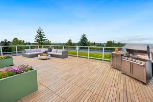 Rooftop deck at Keystone Apartments with outdoor kitchen, stainless steel grill, fire pit, outdoor seating, and planters with flowers