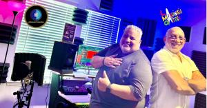 Two music producers, Osmer Martinez and Gianlorett Matos, collaborating at LMG Music Production Studio, surrounded by professional audio equipment.