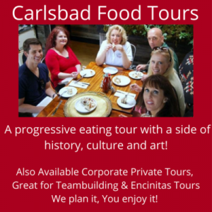 Group of people enjoying a meal at a wooden table, promoting Carlsbad Food Tours that combine cuisine with history and art.