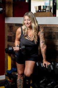 Christina Rondeau former Professional Fighter and Fitness guru holding a dumbbell in a gym