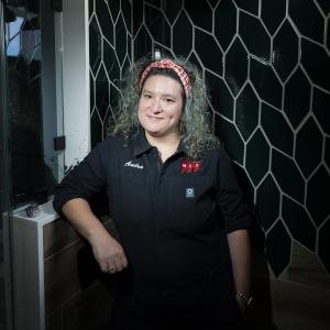 woman with curly hair smiling in a shower with green tiles