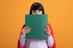 Person holding a large green binder, peeking over it with wide eyes.