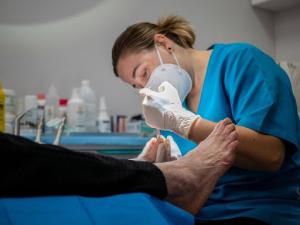 A podiatrist treating a patient’s toenail fungus with a professional laser treatment.