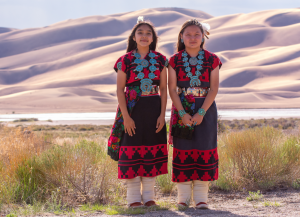  Dineh Tah Navajo Dancers at Great Sand Dunes Park wearing colorful traditional black and red dresses and turquoise jewelry