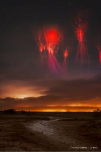 DarkSky International is proud to announce the winners of Capture the Dark 2025, the premier global nighttime photography contest Red bursts of light, known as sprites, illuminate the sky above a field intersected by a dirt path and distance trees.