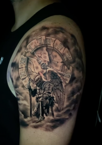 Close-up of a black and grey realism tattoo featuring Archangel Michael and a shattered Roman numeral clock.