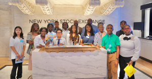 Group of students from the Global Children Financial Literacy Foundation at the New York Stock Exchange, holding financial literacy books during an educational visit.