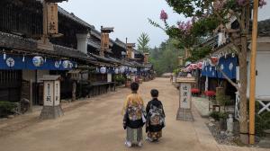 Two boys wearing traditional kimono walking along a historic street lined with shops and lanterns in Nikko, Japan, during a family trip.