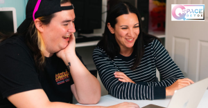 A transgender therapist and a cis female therapist looking at a computer laptop representing affirming therapists at Q Space Detox