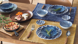 A beautifully set dining table with Nitori's blue and white patterned ceramic plates and bowls, yellow and blue placemats, and wooden utensils, showcasing a complete and coordinated look.