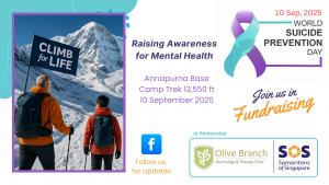 Father and two teenage sons climbing snowy Annapurna Base Camp, holding a ‘Climb for LIFE’ banner, promoting mental health awareness and suicide prevention