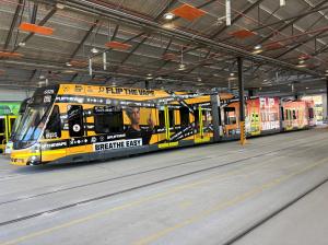 An E-Class tram at the Preston Depot, covered in yellow anti-vaping messaging applied to it.